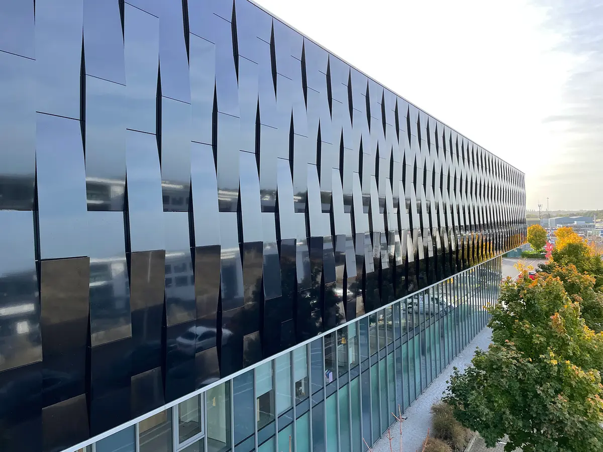 Long dark glazed office building with a glass balustrade and trees alongside